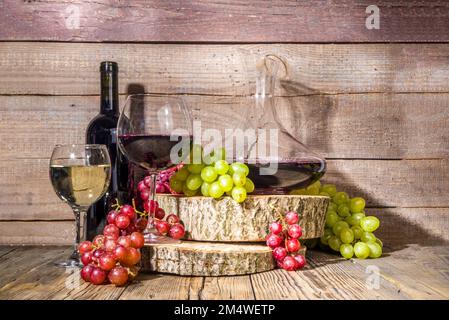 Verres de vin rouge et blanc avec soleil et ombres, avec bouteille et décanter, bouquet de raisins, sur fond de bois avec tourteaux biologiques, autum Banque D'Images