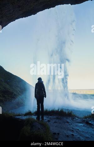 Femme dans la grotte sous la cascade paysage photo Banque D'Images