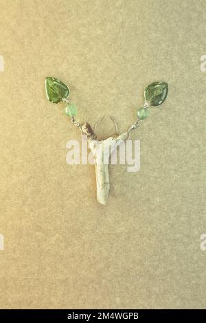 Gros plan des boucles d'oreilles originales avec des feuilles et des perles vertes photo concept Banque D'Images