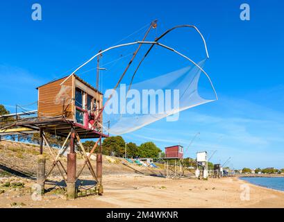 Cabines de pêche avec un grand filet de remontée mécanique carré appelé 'carrelet' aligné sur la plage de Saint-Nazaire, en France, à marée basse lors d'une journée ensoleillée d'été. Banque D'Images