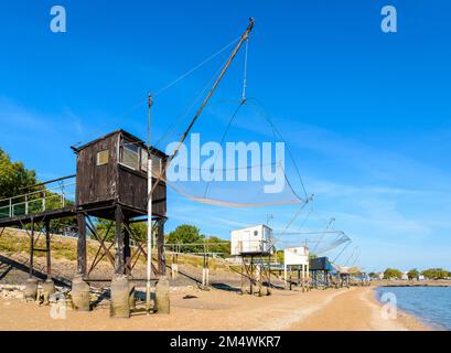 Cabines de pêche avec un grand filet de remontée mécanique carré appelé 'carrelet' aligné sur la plage de Saint-Nazaire, en France, à marée basse lors d'une journée ensoleillée d'été. Banque D'Images