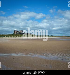 En regardant vers le nord-ouest jusqu'au château historique de Bamburgh à l'horizon au-dessus de la plage de Bamburgh, Northumberland, Royaume-Uni Banque D'Images