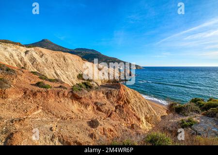 Coucher de soleil sur la plage, falaises et collines et mer d'azur profond. Plage d'Agios Ioannis, île de Milos, Grèce. Banque D'Images