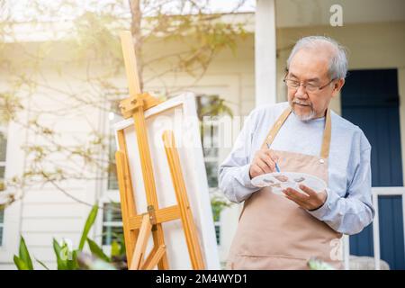Un vieil homme asiatique peint en utilisant la couleur du pinceau et de l'huile sur la toile Banque D'Images