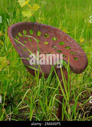 Un siège de tracteur dépasse d'un pré attaché à un morceau de machine qui rousse vers les éléments, Ellison Bay, Door County, Wisconsin Banque D'Images