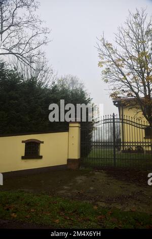 Porte d'un manoir avec haies lors d'une journée de brouillard dans la campagne italienne Banque D'Images