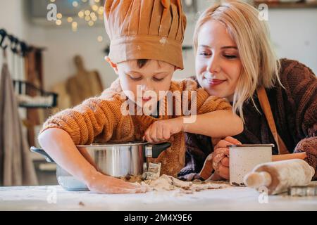 Femme souriante avec son fils préparant des biscuits à la maison Banque D'Images