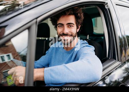 Souriant, beau jeune homme voyageant en voiture Banque D'Images