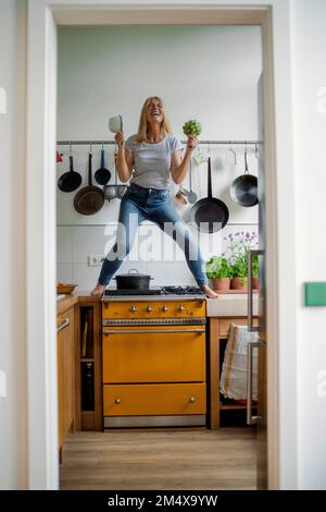 Femme d'âge mûr debout sur la cuisinière appréciant dans la cuisine Banque D'Images