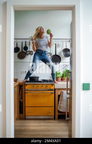 Femme insouciante debout sur la cuisinière en appréciant la danse dans la cuisine Banque D'Images