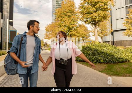 Un jeune couple heureux se tenant les mains et marchant sur le sentier Banque D'Images