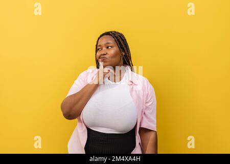 Jeune femme attentionnée debout devant le mur Banque D'Images