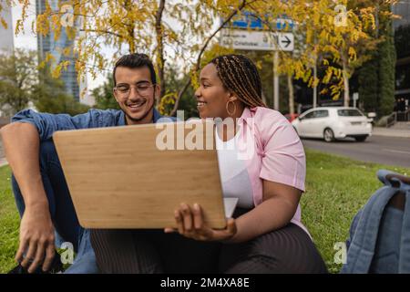 Une femme heureuse avec un homme utilisant un ordinateur portable devant l'arbre Banque D'Images