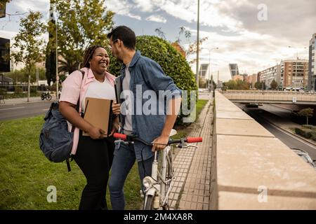 Un jeune couple rit et se tient debout sur la piste cyclable Banque D'Images