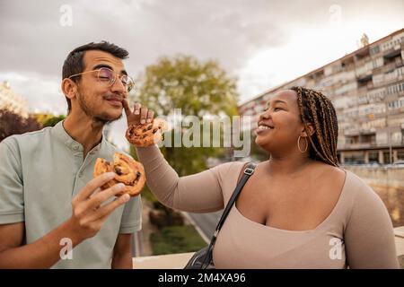 Bonne jeune femme essuyant le visage de l'ami et debout avec des bonbons sous ciel nuageux Banque D'Images