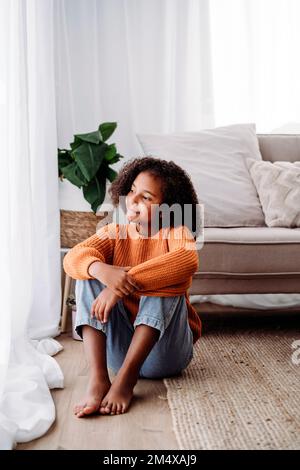 Une fille attentionnés assise dans le salon à la maison Banque D'Images