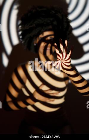 Motif en spirale ombre sur la femme devant le mur Banque D'Images