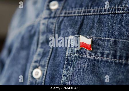 L'écusson en métal avec le drapeau de la Pologne est épinglé sur la veste de Jean bleue. Pologne patriotisme concept. Jour de l'indépendance en Pologne. Banque D'Images