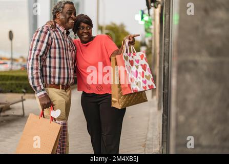 Femme excitée avec des sacs de shopping pointant par l'homme au magasin Banque D'Images
