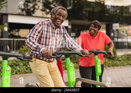 Couple senior joyeux appréciant les uns avec les autres tenant des scooters de poussée Banque D'Images