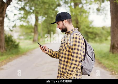 Homme portant une casquette avec un smartphone sur la route Banque D'Images