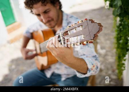 Musicien jouant de la guitare Flamenco assis sur une chaise Banque D'Images