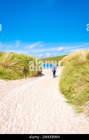 Royaume-Uni, Écosse, marcheur féminin marchant entre les dunes herbeuses de Scousburgh Sands Banque D'Images