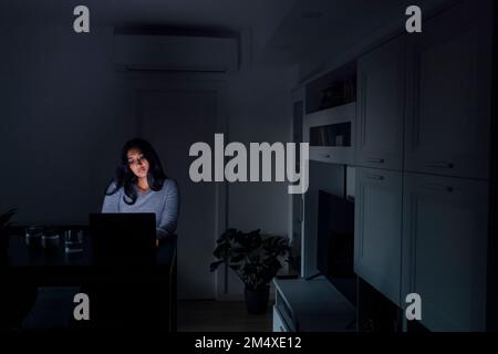 Triste jeune femme utilisant un ordinateur portable dans le salon à la maison Banque D'Images