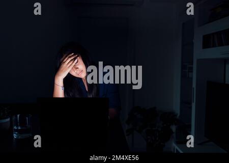 Jeune femme fatiguée avec un ordinateur portable à la maison Banque D'Images