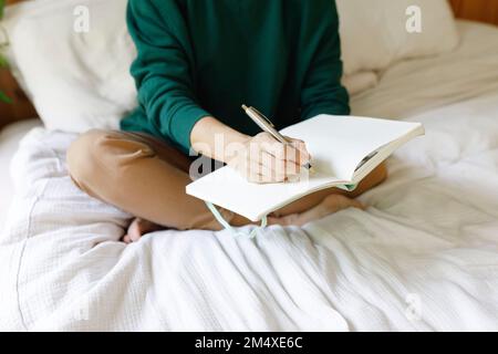 Femme écrivant des notes dans le journal Banque D'Images