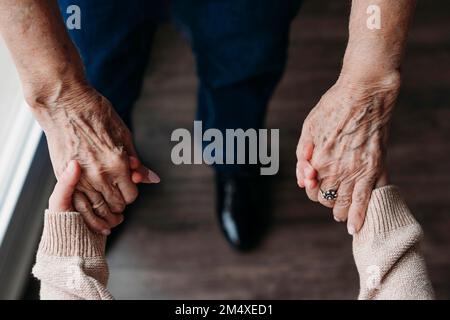 Femme âgée tenant les mains de la petite-fille à la maison Banque D'Images