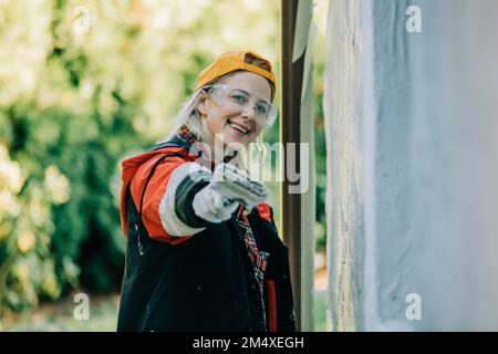 Bonne femme montrant un pinceau devant le mur Banque D'Images