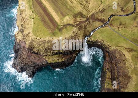 Cascade de Mulafossur au milieu d'une montagne rocheuse par mer Banque D'Images
