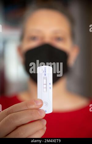 Main d'une femme tenant un dispositif de test positif Banque D'Images