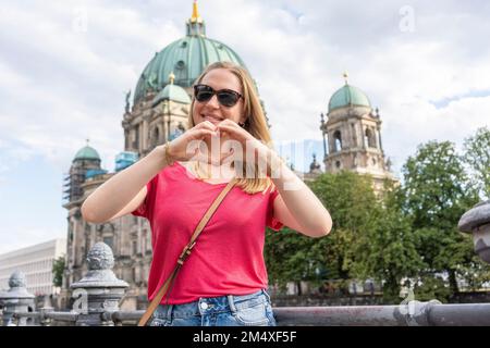 Bonne femme gestante en forme de coeur devant la cathédrale de Berlin, Allemagne Banque D'Images
