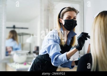 Esthéticienne appliquant le maquillage sur le visage du client dans le salon Banque D'Images