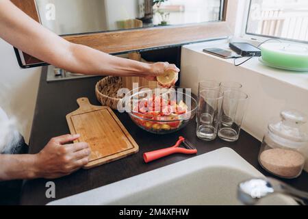 Femme préparant une salade dans la cuisine en serrant le citron Banque D'Images