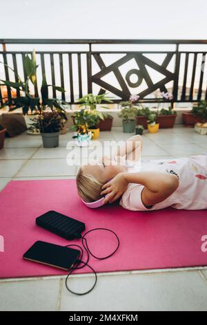 Une fille écoute de la musique avec un casque couché sur la terrasse Banque D'Images