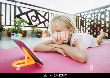 Une jeune fille souriante se détendant sur la terrasse en regardant le téléphone portable Banque D'Images