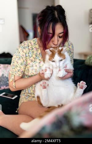 Jeune femme embrassant et jouant avec le chat à la maison Banque D'Images