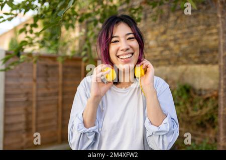 Jeune femme heureuse avec un casque dans le jardin Banque D'Images