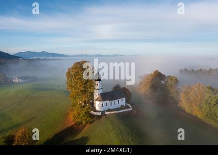 Allemagne, Bavière, Bad Heilbrunn, vue aérienne de l'église de Visitation de la Vierge Marie à l'aube brumeuse de l'automne Banque D'Images