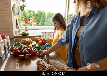 Mère et fille déballant des produits d'épicerie frais dans la cuisine Banque D'Images