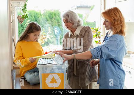 Grand-mère, mère et fille trient les déchets de recyclage dans la cuisine Banque D'Images