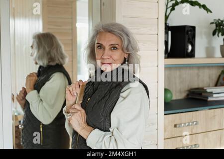 Portrait d'une femme âgée confiante devant le miroir à la maison Banque D'Images