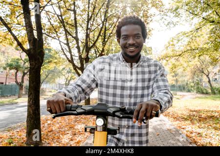 Homme debout sur la voie de passage avec un scooter-poussoir électrique Banque D'Images