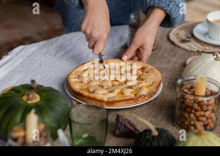 Mains de femme coupant la tarte à la citrouille maison Banque D'Images