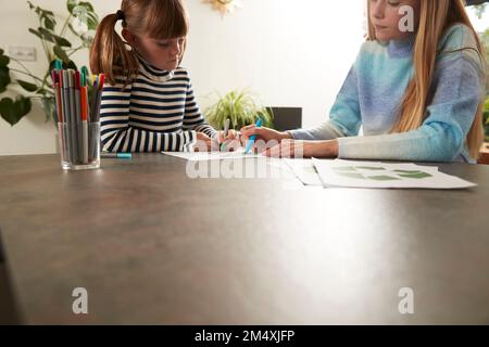 Les filles dessinant sur du papier avec un stylo à la maison Banque D'Images