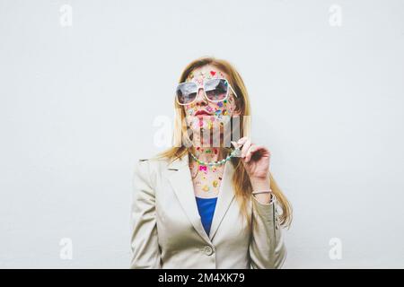 Femme avec des autocollants colorés sur le visage devant un fond blanc Banque D'Images