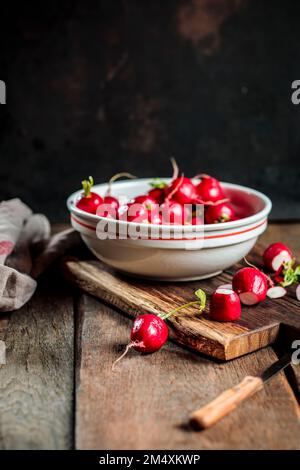 Radis frais dans un bol avec couteau sur la table Banque D'Images